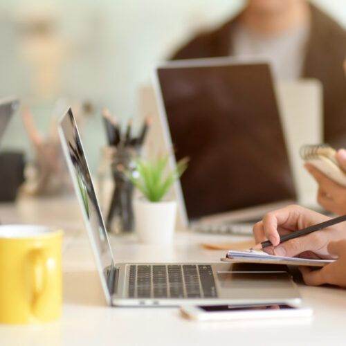 Side view of businesspeople meeting on their project with digital device and office supplies on white desk